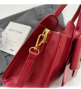 Detailed macro view of high-gloss red leather handbag with premium golden metal hardware