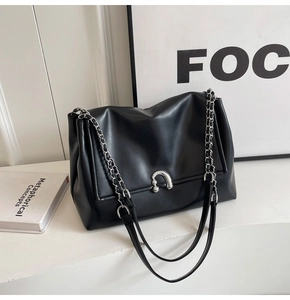 Close-up of black leather underarm bag featuring silver chain and metal buckle detail