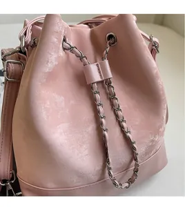 Detail of pink leather bucket bag with metal chain drawstring and textured finish