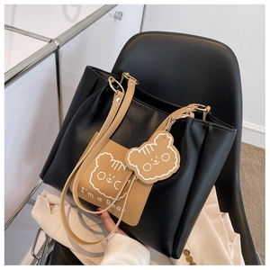 Detail of a large leather tote bag with a cartoon bear print and matching charm