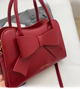 Detail of red bridal leather handbag with large bow and gold fashion lettering