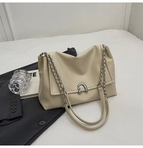 Detail of minimalist beige shoulder bag showing smooth leather and silver metal clasp