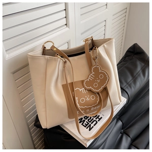 Detail of a large cream tote bag with brown bear pocket and matching cute bear keychain