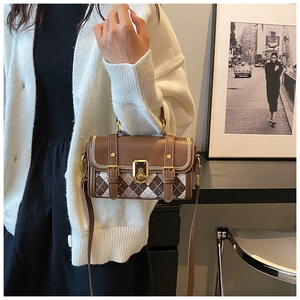 Detail view of British style satchel with brown checkered pattern and gold metal hardware