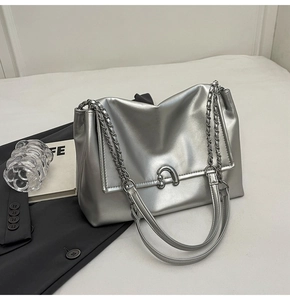 Detail of silver metallic tote bag with U-shaped metal buckle and chain shoulder strap