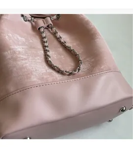 Detail of pink bucket bag featuring drawstring closure, chain strap and metal bottom studs