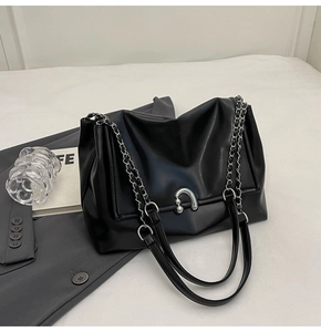 Detail of black faux leather hobo bag with silver U-shaped buckle and chain strap