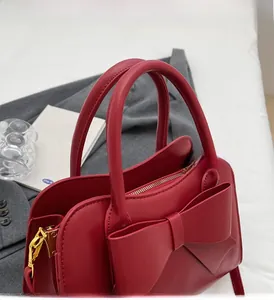 Detail of red bridal handbag featuring a large bow knot and golden metal zipper hardware