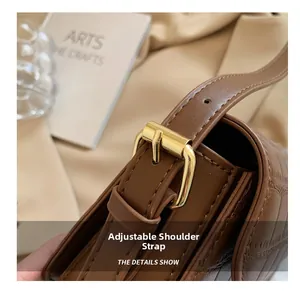 Detail of adjustable strap with gold buckle on brown crocodile texture leather bag