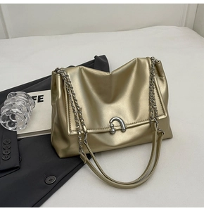 Detail of a golden metallic shoulder bag with silver U-shaped buckle and chain strap