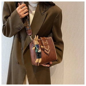 Braune Vintage-Quadrat-Tasche mit V-Nähten und buntem gewebtem Gurt an einem Model