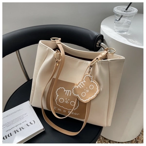 Detail of minimalist cream tote bag featuring brown contrast leather bear print