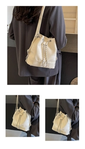 Detail of off-white drawstring bucket bag with silver chain and slim shoulder strap