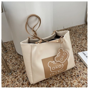 Detail of minimalist cream tote bag with brown front pocket featuring a cute bear print