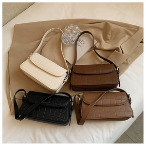 Detail view of four crocodile embossed baguette bags in beige, brown, and black
