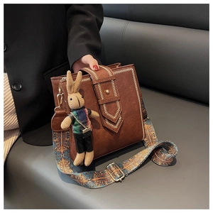 Details der braunen PU-Ledertasche mit Webstichen und gemustertem Schultergurt