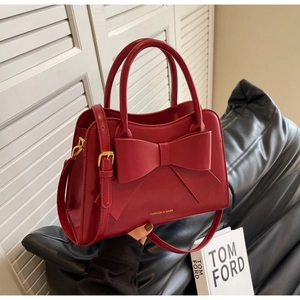 Detailed shot of a red bridal handbag featuring a large bow and adjustable gold buckle strap