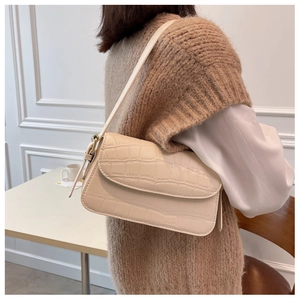 Close-up of cream crocodile pattern shoulder bag featuring refined gold-tone buckle detail