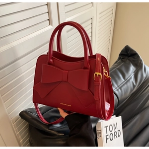 Red bridal handbag featuring a large stylish bow and golden logo with slim shoulder strap