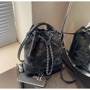 Close-up of black bucket bag featuring metallic gold splatter texture and chain drawstring