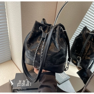 Detail showing distressed black gold bucket bag with metallic texture and MAO BAGS logo