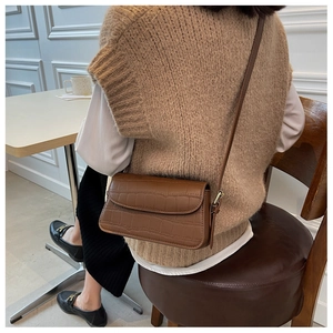 Detailed view of a brown crocodile pattern leather shoulder bag with a sleek flap closure