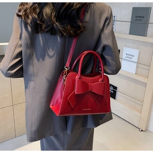 Detail shot of a red bridal handbag with bow accent worn crossbody style outdoors