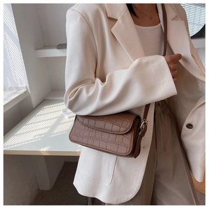 Close-up of brown crocodile pattern shoulder bag with flap closure and metallic hardware