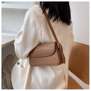 Detailed close-up of brown crocodile texture material and golden buckle on shoulder bag