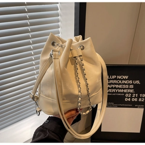 Detailed shot of cream bucket bag featuring silver chain handle and drawstring closure
