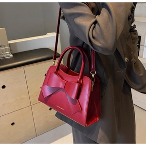 Side view of red bridal handbag with bow detail and gold lettering on shoulder strap