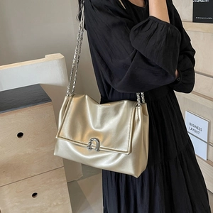 Chic champagne gold shoulder bag with silver chain strap shown in a stylish interior