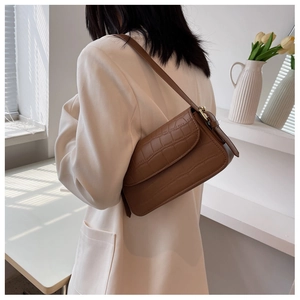 Detail view of coffee brown crocodile pattern shoulder bag on white blazer outfit