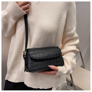 Close-up of black crocodile pattern crossbody bag with golden hardware on model