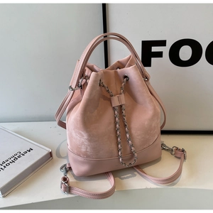 Detailed shot of pink bucket bag featuring suede texture and silver chain drawstring closure