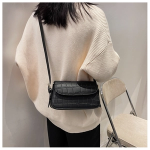 Close-up of black crocodile pattern crossbody bag with a slim strap and flap closure