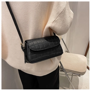 Classic black crocodile texture crossbody bag shown on a model in a minimalist setting