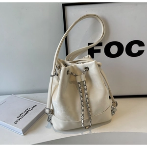 Close-up of beige bucket bag with silver chain drawstring and matte texture
