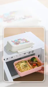 Detail of hand placing cartoon unicorn double-layer lunch box into microwave oven