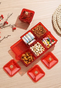 Close-up of red translucent divided snack tray with gold handles on a wooden table