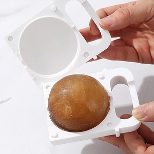 DIY silicone spherical ice ball mold with large coffee-colored ice cube being removed