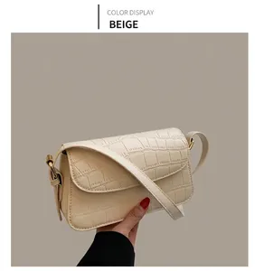 Close-up of cream white crocodile texture bag with gold hardware on beige aesthetic background