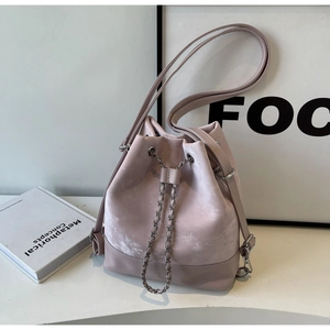 Detail of pink drawstring bucket bag with metal chain and adjustable leather strap