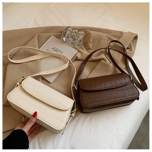 Detail view of retro crocodile pattern shoulder bags in cream and dark brown with gold hardware