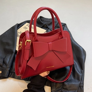 Elegant red bridal handbag with large bow decoration and gold lettering on black jacket