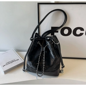 Detail of black velvet bucket bag showing silver chain drawstring and leather texture