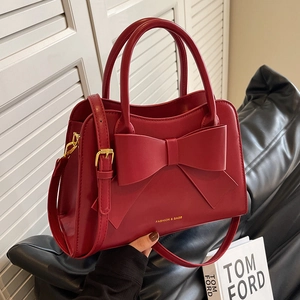 Elegant red bridal handbag with a large bow detail and adjustable gold shoulder strap
