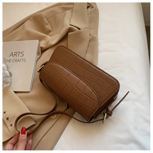 Detail of vintage brown crocodile embossed leather bag with gold hardware and flap closure