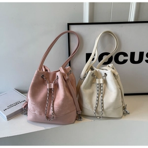 Detail of suede bucket bags with drawstring closure and chic metal chain straps