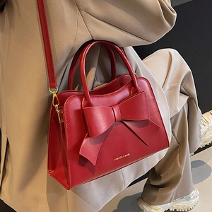 Elegant red leather bridal handbag with a large bow detail and stylish gold accents